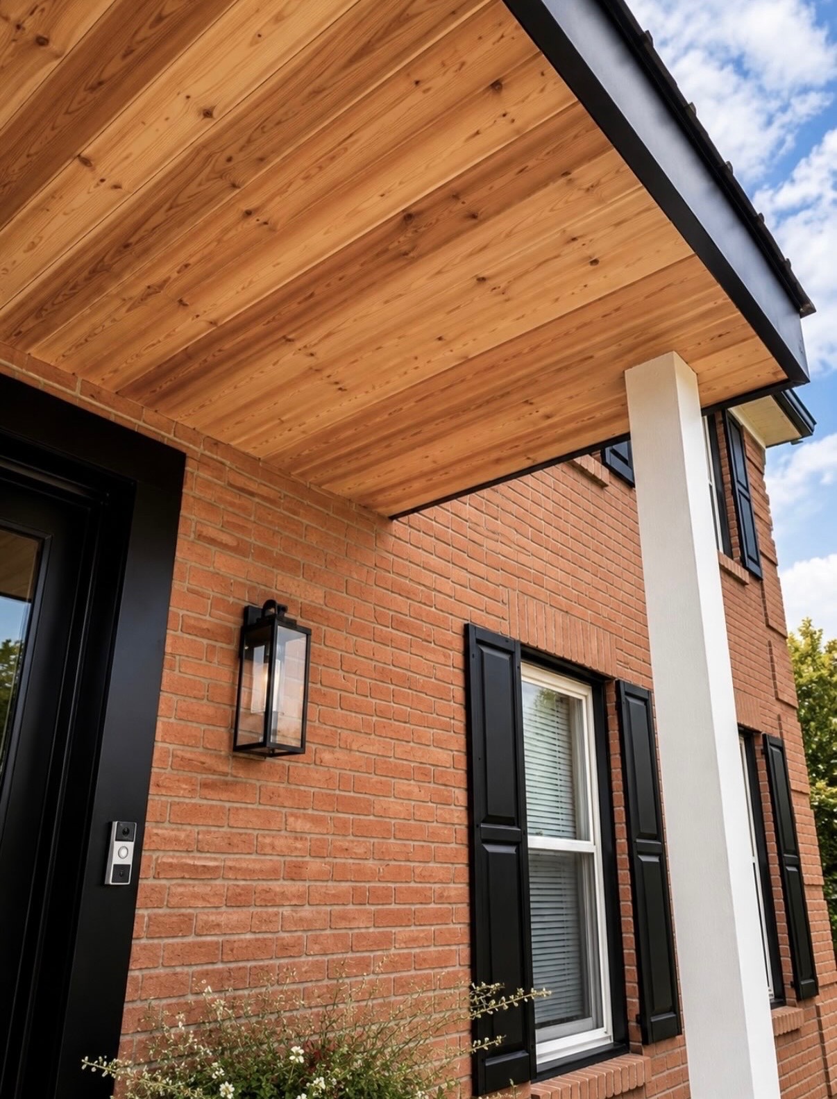 Brick front entry with black shutters and a natural cedar porch ceiling