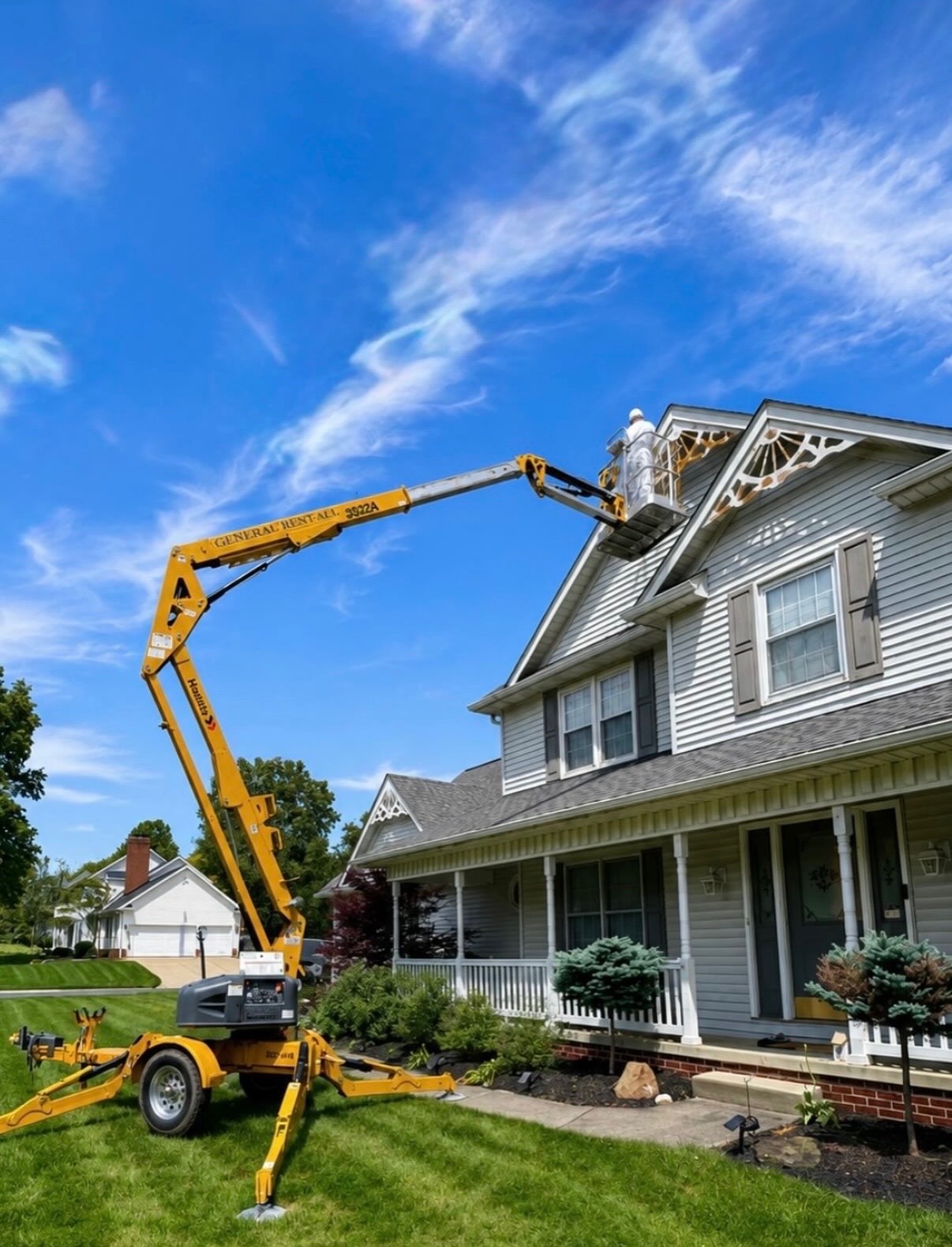 Exterior painting crew using a lift to reach decorative gable trim