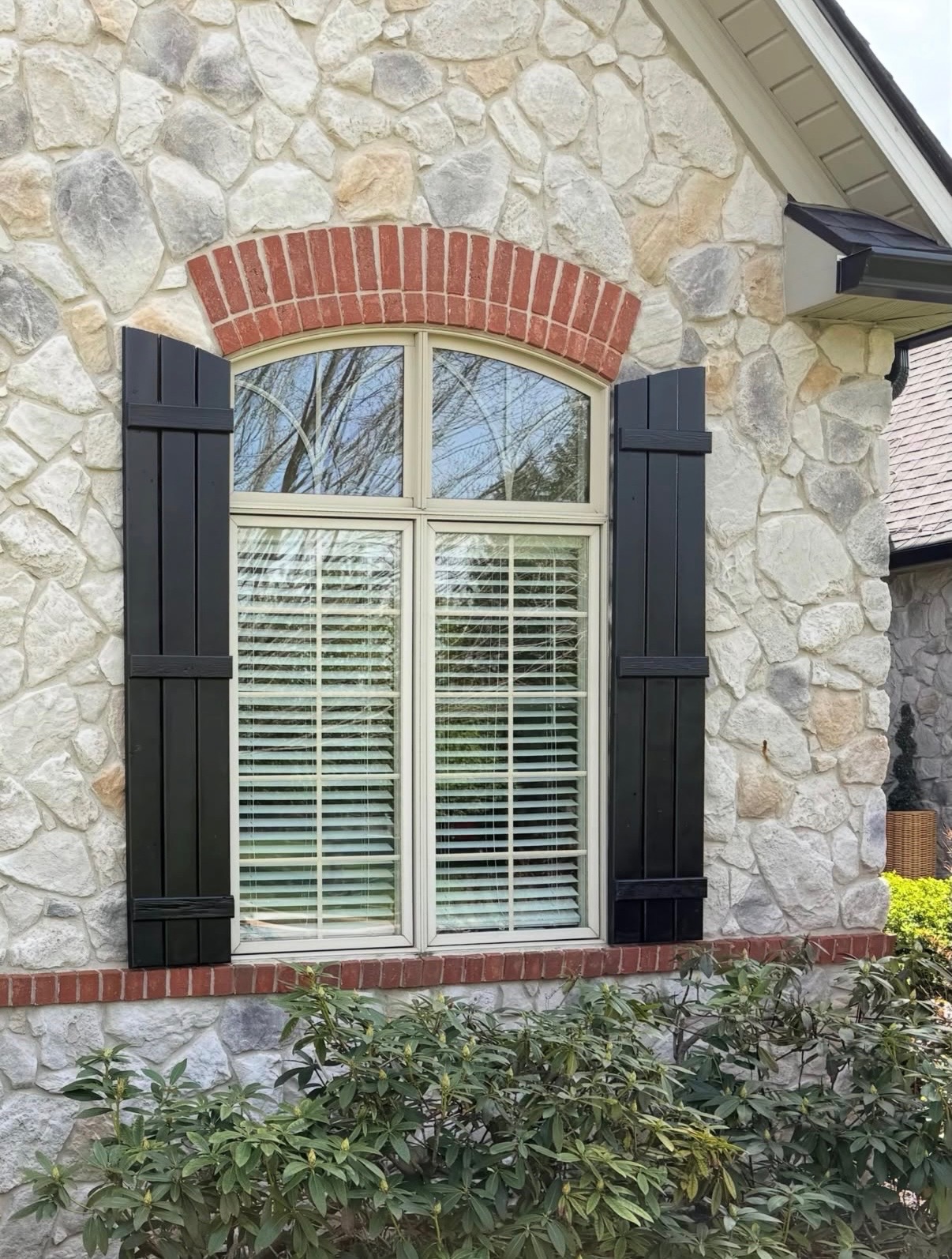 Stone home with freshly finished black window shutters